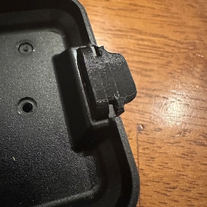 May include: A black plastic case with a latch on the top. The latch is closed.