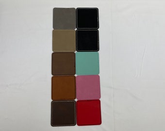 May include: Ten square coasters in various colors, including gray, black, beige, brown, light blue, pink, and red. The coasters are made of a soft, textured material and have a stitched edge.