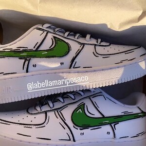 以下が含まれることがあります： 緑と黒の漫画風のナイキのスウッシュがついた白いスニーカー。靴は、側面にInstagramのハンドル@labellamarposacoが書かれた箱に入っています。