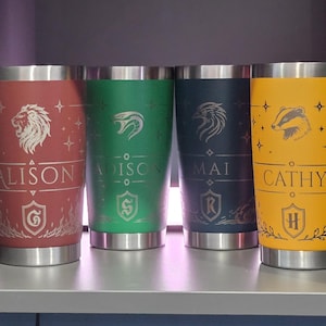 May include: Four stainless steel tumblers in red, green, dark blue, and yellow. Each features a unique animal emblem, a shield icon, and a personalized name: ALISON, ADISON, MAI, and CATHY. The designs include stars and decorative line work.