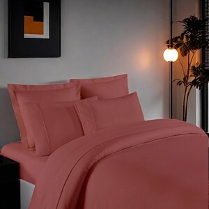 May include: A red duvet cover and pillowcases set on a bed. The bedding is made of a soft, smooth fabric.