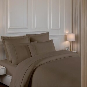 May include: A brown duvet cover and pillowcases set on a bed with a white headboard. The bedding is made of a soft, smooth fabric.