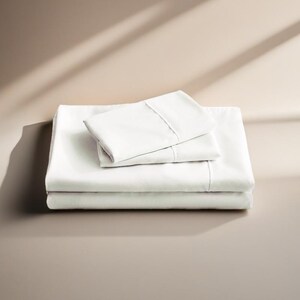 May include: A set of white cotton bed sheets, folded neatly. The sheets are made of a soft, breathable fabric and are perfect for a comfortable night's sleep.