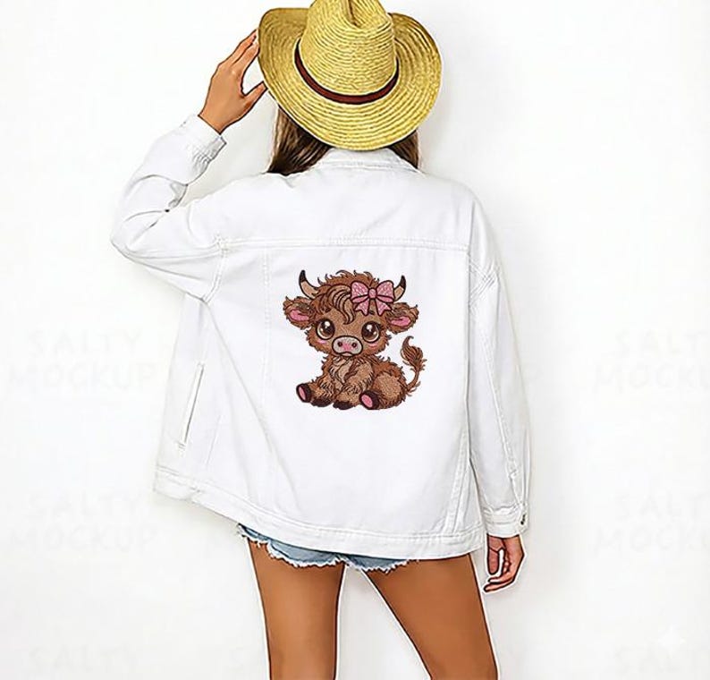 May include: White denim jacket with a cartoon Highland cow and a pink bow. The jacket has a classic design with a button-up front, pockets, and a collar. The cow graphic is embroidered on the back.