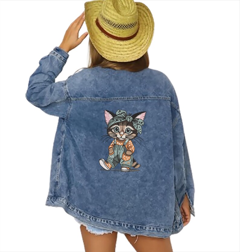 Puede incluir: Chaqueta vaquera azul claro con un dibujo de gato de dibujos animados en la espalda. El gato lleva un peto y una diadema. La chaqueta tiene un cuello cl&aacute;sico y cierre de botones.