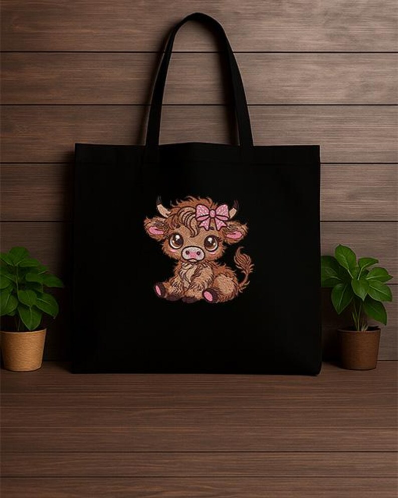 May include: Black tote bag with an embroidered Highland cow design. The cow is brown with a pink bow, large eyes, and pink details. The bag has black handles and is made of a durable material. The design is a charming illustration.