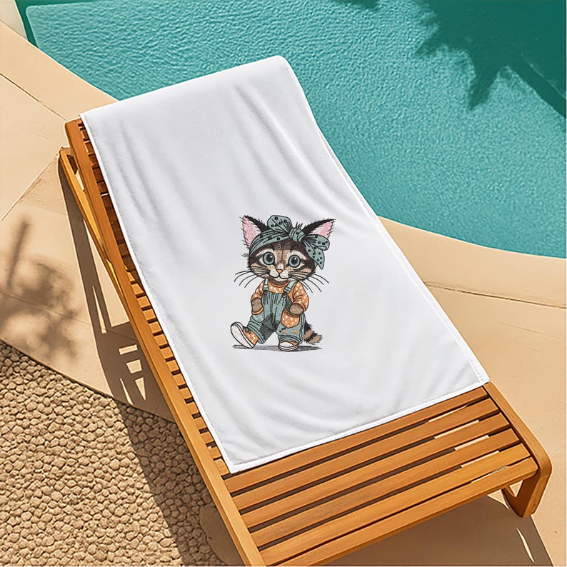 Puede incluir: Toalla de playa blanca con una ilustraci&oacute;n de dibujos animados de un gato con peto y diadema. El gato es marr&oacute;n, gris y naranja. La toalla est&aacute; sobre una tumbona de madera junto a una piscina.