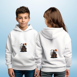 May include: White hooded sweatshirts with a Halloween-themed graphic. The graphic features a haunted house, bats, a bare tree, and an orange moon. The sweatshirts have a front pocket and are worn by two children.