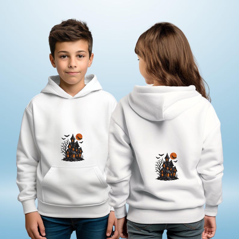 May include: White hooded sweatshirts with a Halloween-themed graphic. The graphic features a haunted house, bats, a bare tree, and an orange moon. The sweatshirts have a front pocket and are worn by two children.