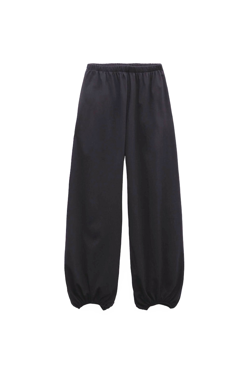 Pu&ograve; includere: Pantaloni neri a tinta unita caratterizzati da una silhouette ampia e rilassata, con vita elasticizzata e polsini arricciati con elastico alle caviglie. Il capo &egrave; realizzato in un tessuto liscio e opaco di un colore scuro uniforme.