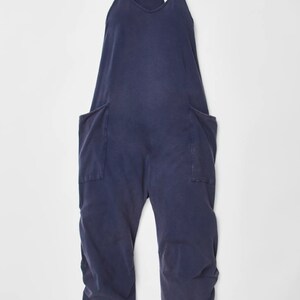 May include: A dark blue sleeveless jumpsuit with two large pockets on the front. The jumpsuit has a V-neck and thin straps.