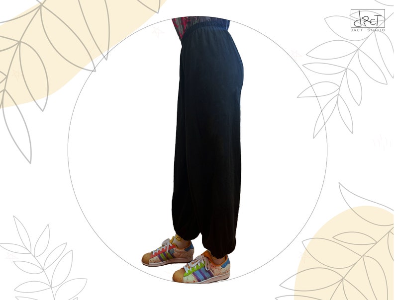 Pu&ograve; includere: Pantaloni neri a tinta unita dal taglio ampio con vita elasticizzata e polsini arricciati alle caviglie. I pantaloni sono abbinati a scarpe da ginnastica basse con un motivo a righe multicolore, lacci bianchi e punta in gomma testurizzata.