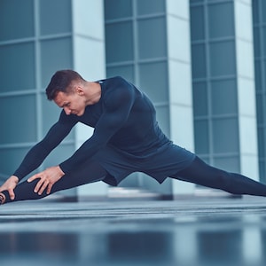 May include: A long-sleeved black compression shirt, black athletic shorts, black leggings, and black sneakers. The outfit is designed for athletic performance and flexibility, featuring a sleek, monochromatic aesthetic with fitted fabric.