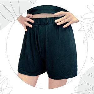 May include: Solid black shorts featuring an elasticized waistband and a relaxed fit. The garment is plain, unpatterned, and reaches mid-thigh. The fabric appears smooth and lightweight, designed with a simple pull-on style for ease of wear.