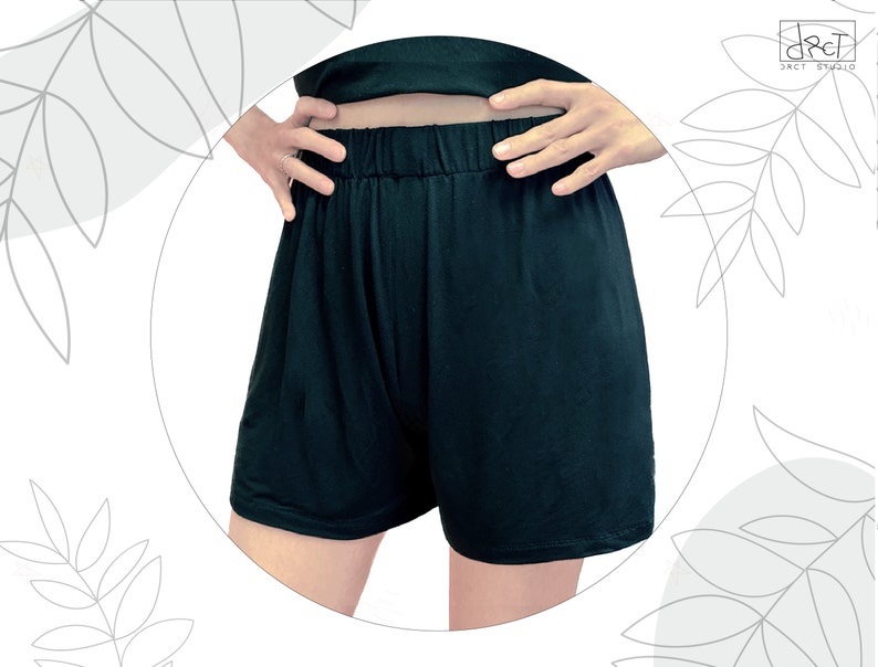 May include: Solid black shorts featuring an elasticized waistband and a relaxed fit. The garment is plain, unpatterned, and reaches mid-thigh. The fabric appears smooth and lightweight, designed with a simple pull-on style for ease of wear.