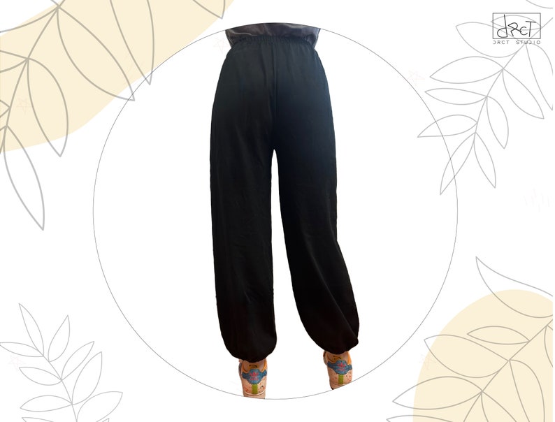 Pu&ograve; includere: Pantaloni neri a tinta unita con vita alta, elastico in vita e una silhouette a gamba larga e rilassata che si restringe leggermente alle caviglie. I pantaloni sono mostrati di schiena, evidenziando una struttura semplice e priva di decorazioni.