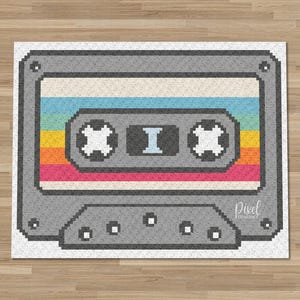 Può includere: Un design di nastro per cassette grigio con un motivo a strisce arcobaleno retrò. Il nastro presenta un design pixelato con la lettera "I" al centro. La parola "pixel" si trova nell'angolo in basso a destra.