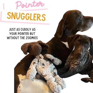 May include: Two brown and white German Shorthaired Pointer dogs, one sitting and one lying down, with a brown and white crocheted plush dog toy. The text "Pointer Snugglers" is in the top left corner of the image. The text "Just as cuddly as your pointer but without the zoomies" is in the bottom left corner of the image.