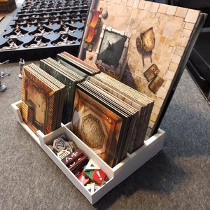 May include: White plastic organizer with multiple compartments for storing game pieces and cards. The organizer has a compartment for cards, a compartment for tokens, and a compartment for tiles. The organizer is filled with game pieces and cards.