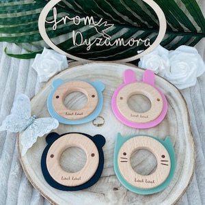 May include: Four wooden teething rings with different animal shapes and colors. The rings are made of natural wood and have a smooth, rounded surface. The rings are perfect for babies to chew on and help soothe their gums.