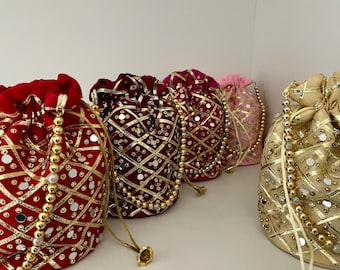Puede incluir: Cinco bolsas de cordón con adornos dorados y plateados. Las bolsas están hechas de tela y tienen una variedad de colores, incluyendo rojo, rosa y dorado.