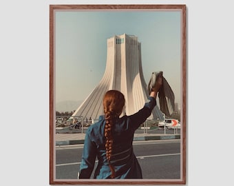 May include: A woman with long red hair stands in front of a large, white building with a tower. She is wearing a blue jacket and is holding a blue cloth in her right hand. The building is in the background and the woman is in the foreground.