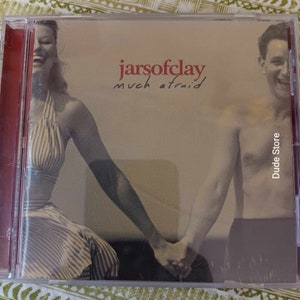Può includere: Una custodia per CD con una foto di un uomo e una donna che si tengono per mano. La copertina dell'album è per la band Jars of Clay e il titolo dell'album è "much afraid". Il testo "Dude Store" è stampato sul lato destro della custodia.