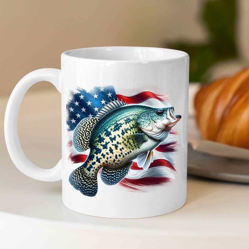 Op de afbeelding: Witte keramische koffiemok met een kleurrijk beeld van een baars die voor een Amerikaanse vlag zwemt.