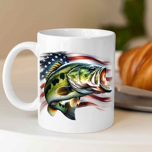 Pu&ograve; includere: Tazza da caff&egrave; in ceramica bianca con una grafica di un basso a bocca larga che salta fuori dall'acqua davanti a una bandiera americana.
