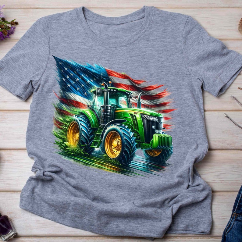 K&ouml;nnte beinhalten: Ein graues T-Shirt mit einem gr&uuml;nen Traktor, der vor einer zerfetzten amerikanischen Flagge f&auml;hrt.