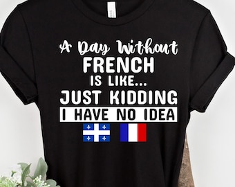 May include: Black t-shirt with white text that reads "A Day Without French is Like... Just Kidding I Have No Idea". The shirt also features the flags of Quebec and France.