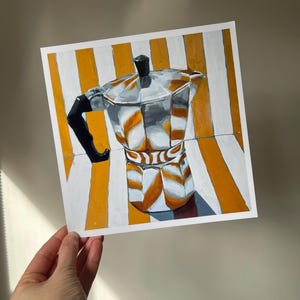 Puede incluir: Una cafetera plateada y negra sobre un fondo rayado amarillo y blanco.