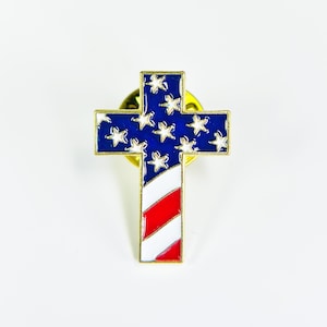 May include: A gold-colored metal pin in the shape of a cross with the American flag design. The cross is decorated with red, white, and blue enamel.