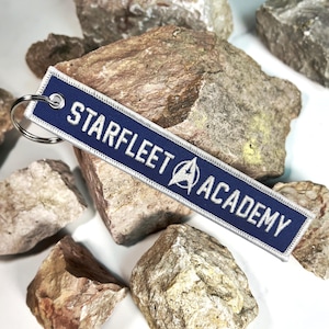 May include: A blue and white key chain with the text "Starfleet Academy" and the Starfleet logo.