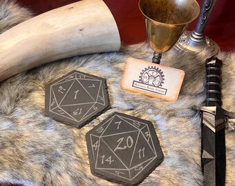Juego de 2 posavasos de pizarra con dado de 20 caras y números de fantasía.