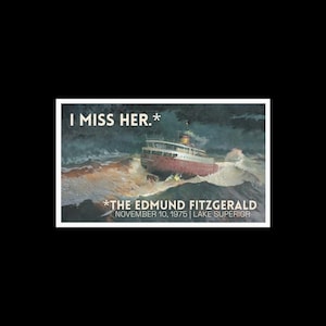Peut inclure: Une impression représentant un navire en mer agitée, avec le texte "I MISS HER.*" en haut. En dessous du navire, le texte indique "*THE EDMUND FITZGERALD NOVEMBER 10, 1975 | LAKE SUPERIOR". Le navire est rouge et blanc.