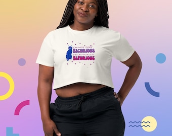 May include: A cream-coloured crop top featuring the text "I'M NOT JUST BICHURIOUS I'M ACTUALLY BIFURIOUS" and a blue cat illustration. The top is worn with black athletic trousers. The design has a playful, graphic style.
