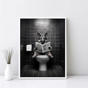 Può includere: Stampa incorniciata in bianco e nero con un cane pastore tedesco seduto su un water che legge un giornale. Il cane si trova in un bagno piastrellato di nero con un rotolo di carta igienica. Un vaso bianco con steli verdi è in primo piano.