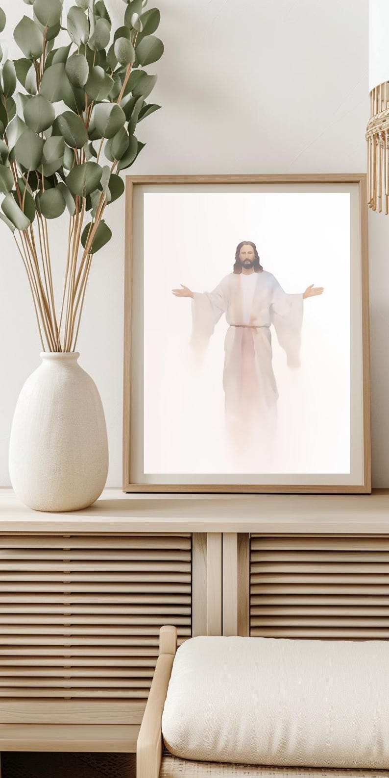 May include: A framed print of a painting depicting a man in a white robe with his arms outstretched. The background is a soft white with a light pink glow.