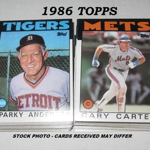 May include: A stack of 1986 Topps baseball cards. One card features Sparky Anderson, the Detroit Tigers manager, and the other features Gary Carter of the Mets. The cards have a white border with team names in bold text.