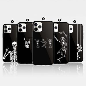 May include: Five black phone cases with different skeleton designs. The designs include a skeleton playing guitar, a skeleton with a peace sign, a skeleton dancing, a skeleton with a rock and roll hand gesture, and a skeleton hanging from a swing.