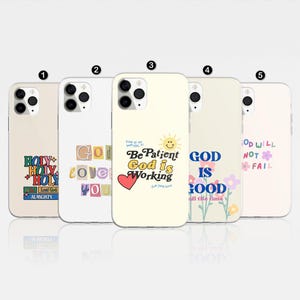 May include: Five phone cases with inspirational quotes. The cases are in various colors, including cream and white. Each case features a different design with phrases like "Holy," "God is Good," and "God is Working." The cases have a glossy finish.