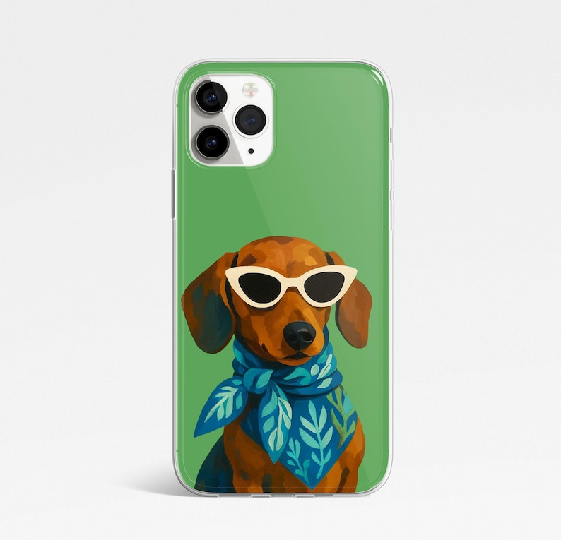May include: A clear phone case featuring a dachshund wearing white sunglasses and a blue scarf with a leaf pattern. The dog is brown with dark brown ears and nose. The background is a solid green.