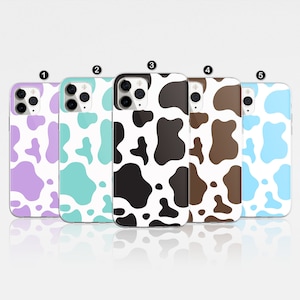 May include: Five different phone cases featuring a cow print design. The cases are available in a range of colours, including purple, blue, black, brown, and light blue.