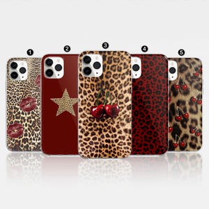 May include: Five different iPhone cases with a leopard print design. The cases feature different designs, including a red star, a red cherry, and a red heart.