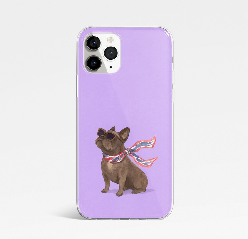 May include: A phone case with a watercolor illustration of a brown French bulldog wearing sunglasses and a red, white, and blue scarf. The case has a lavender background and a clear, glossy finish.