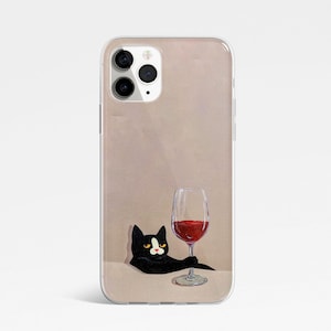 Pu&ograve; includere: Un gatto nero con macchie bianche &egrave; seduto su uno sfondo marrone chiaro, guardando un bicchiere di vino rosso. Il gatto tiene il bicchiere con la zampa. La custodia del telefono &egrave; trasparente e ha un bordo bianco.