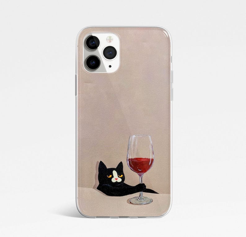 Pu&ograve; includere: Un gatto nero con macchie bianche &egrave; seduto su uno sfondo marrone chiaro, guardando un bicchiere di vino rosso. Il gatto tiene il bicchiere con la zampa. La custodia del telefono &egrave; trasparente e ha un bordo bianco.