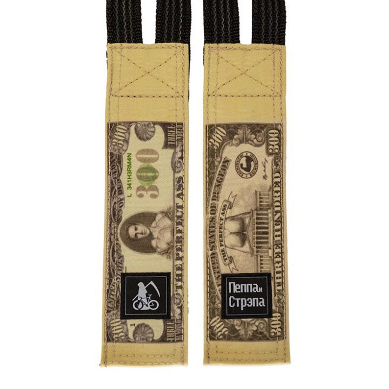 Puede incluir: Dos correas de tela beige con un dise&ntilde;o que se asemeja a un billete de $300. Las correas presentan el texto "THE PERFECT ASS" y "Пеппа и Стрэпа". Cada correa tiene un logotipo en blanco y negro de una bicicleta y una guada&ntilde;a.