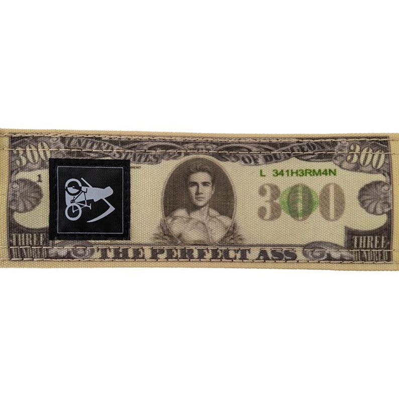 Puede incluir: Parche rectangular beige que se asemeja a un billete de 300 d&oacute;lares, con un retrato y el texto "THE PERFECT ASS". Un cuadrado negro con un gr&aacute;fico blanco a la izquierda.